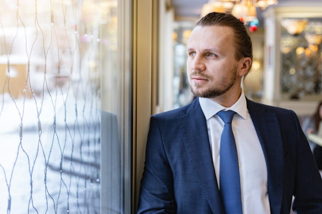 Man standing and looking dreamly in the window indoor - Image